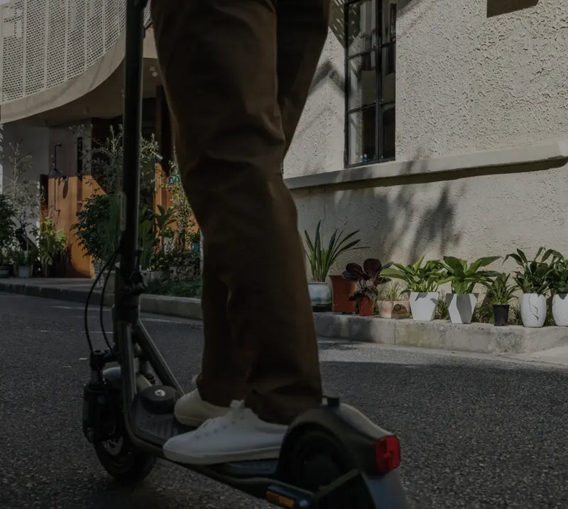 Conducteur sur la trottinette Segway Ninebot F2 E II en ville, détail du repose-pied