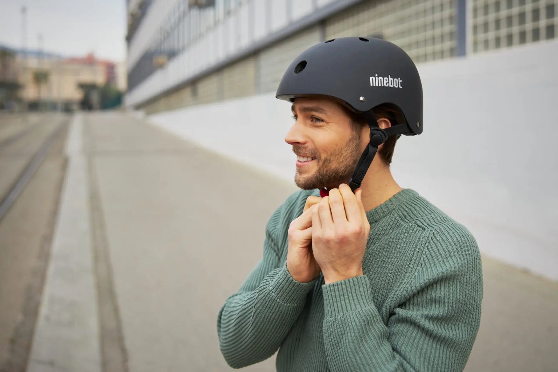 Homme portant le casque Segway Ninebot et attachant la sangle en ville