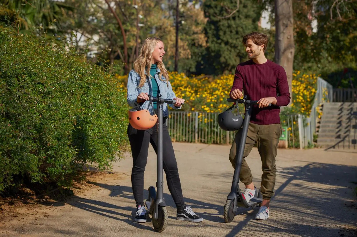 Deux personnes avec casques Segway Ninebot et trottinettes dans un parc